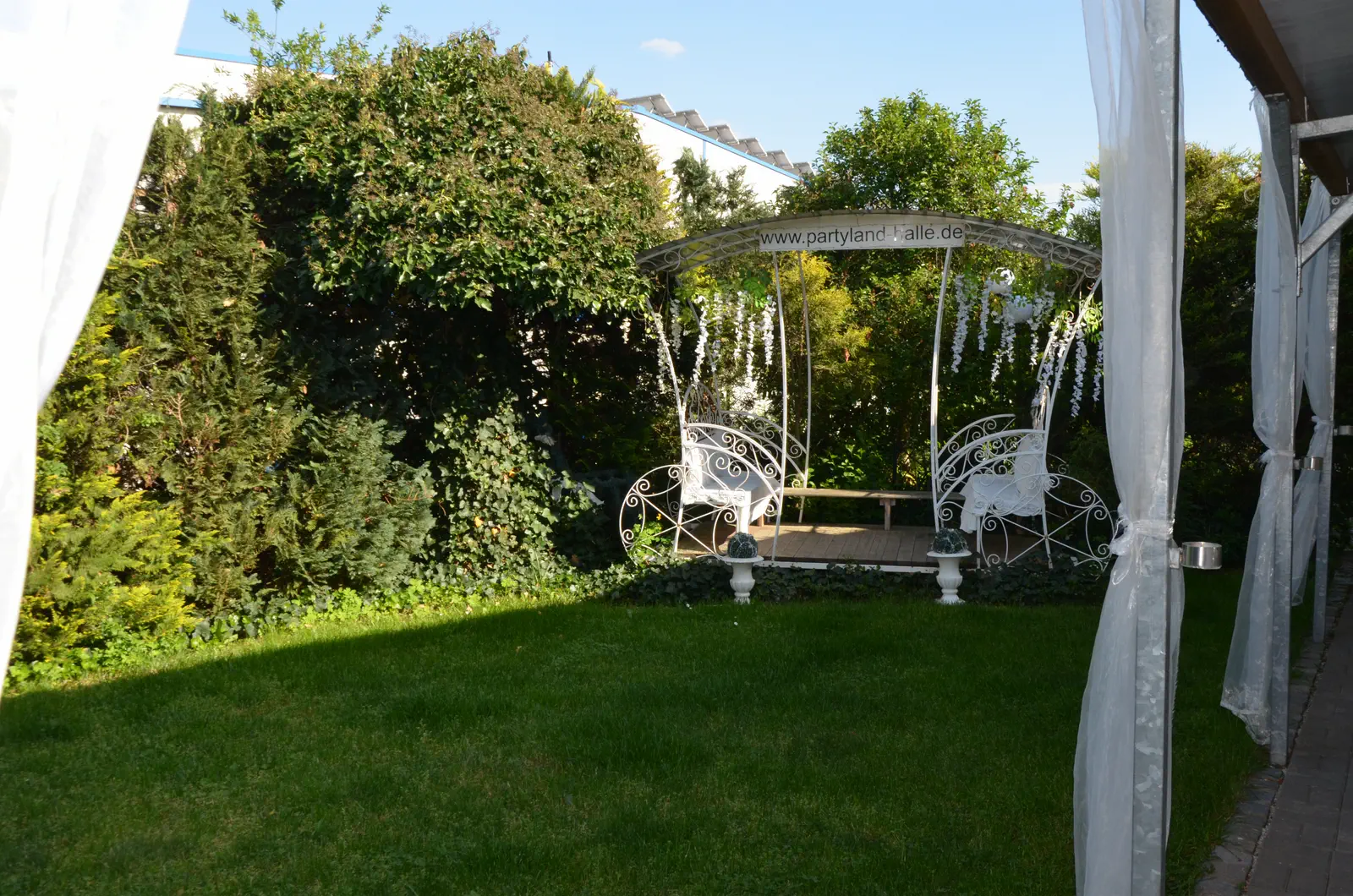 Der Garten hinter der Halle mit Pavillon und Schaukelbank