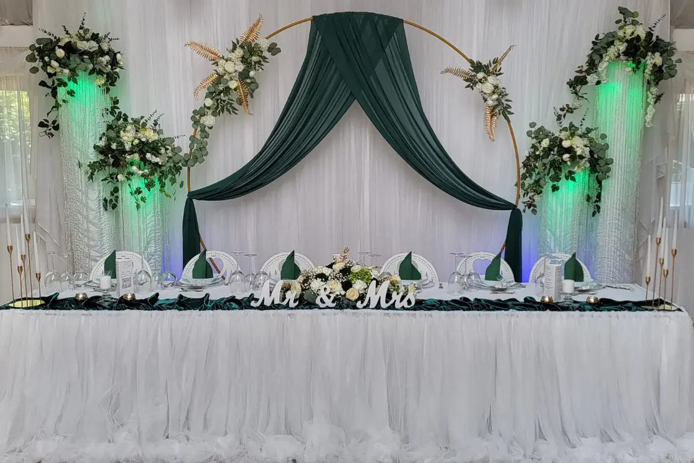 Brauttisch mit goldenem Ring, dunkelgrüner Stoffdraperie und weißen Blumen
